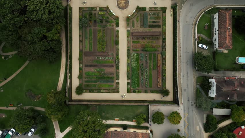 Aerial view of the kitchen garden, a verdant patchwork of plots and paths, contrasting with the surrounding trees and buildings, Prangins, Vaud, Switzerland.