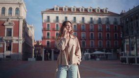 Young beautiful woman talking on the phone and waving in a city square on a sunny day - Powered by Shutterstock - Get 15% off with code: PIKWIZARD15