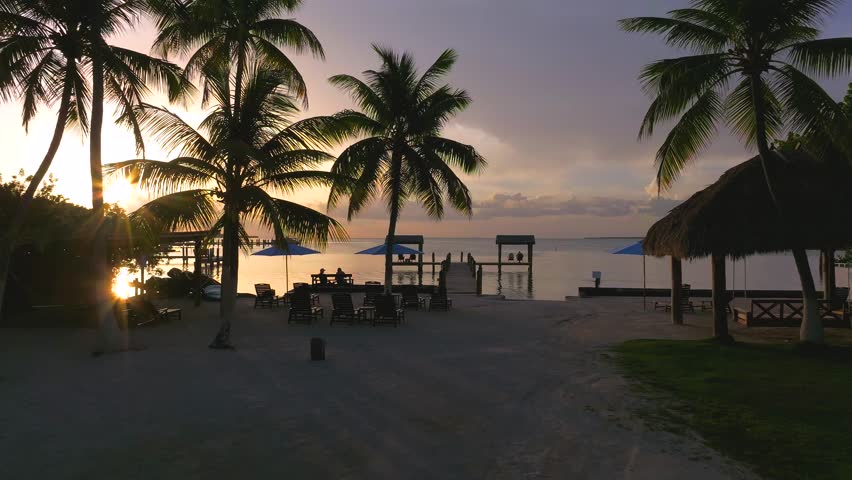 Aerial view of docks extending into the tranquil ocean, kissed by the golden hues of the setting sun, creating a serene scene, Key Largo, Florida, United States.