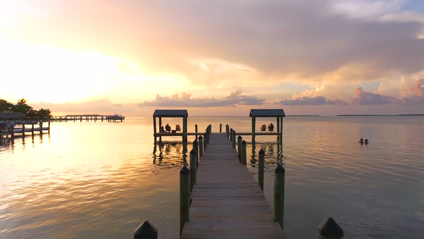 Aerial view of docks with boats resting on calm waters reflecting the golden hues of the sunset, Key Largo, Florida, United States.