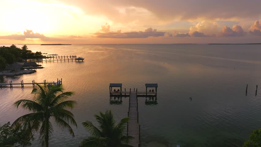 Aerial view of docks stretching over the calm water at sunset, with the sky painted in hues of gold and purple, Key Largo, Florida, United States.