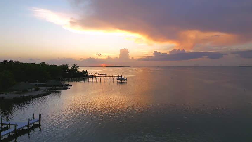 Aerial view of docks stretching into the tranquil waters, reflecting the vibrant sunset hues in Key Largo, creating a picturesque scene, Key Largo, Florida, United States.
