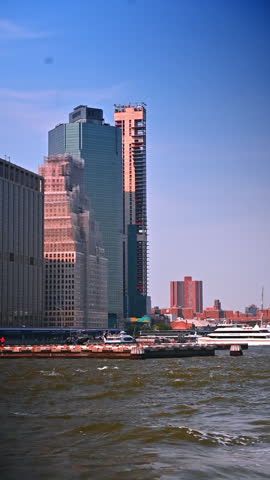 New York, USA, 29 July 2025: Modern glass skyscrapers reflecting sunlight in New York. Downtown New York skyscrapers reflecting warm sunlight on glass facades along the waterfront skyline.