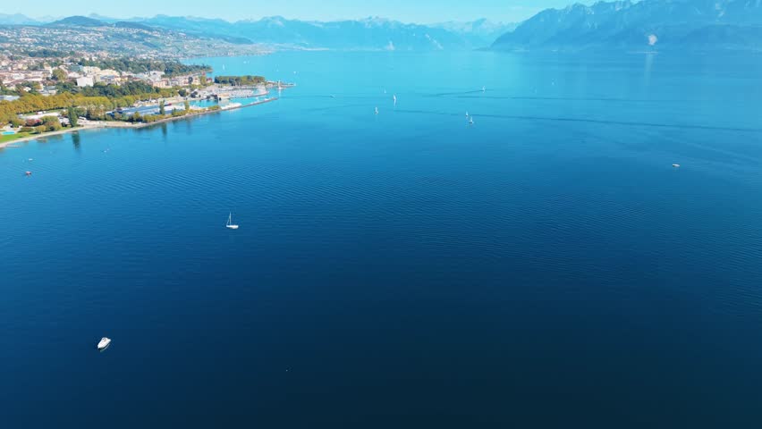 Aerial view of the Lausanne cityscape where the buildings meet the tranquil blue waters of the lake, reflecting the clear sky, Lausanne, Vaud, Switzerland.