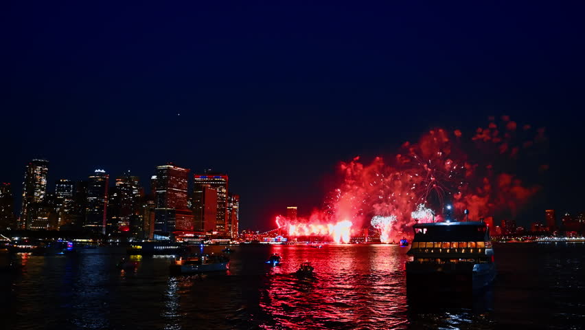 Fireworks over New York City skyline at night. Bright fireworks light up the night sky above the New York City skyline with reflections in the river.
