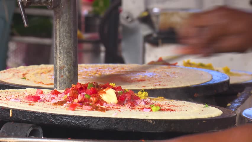 Street food vendors making savory dosa crepes, a traditional South Indian cuisine