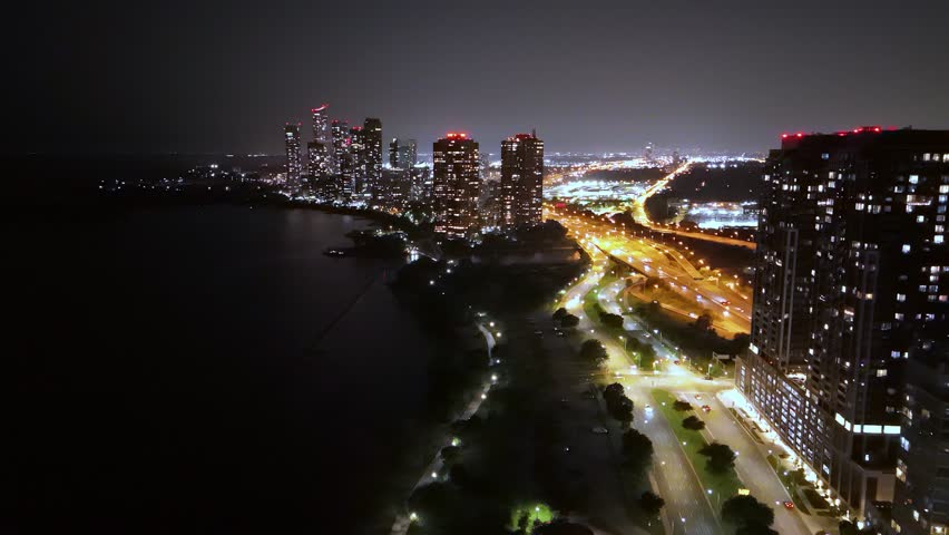 Drone shot at night over Lake Ontario showing Parklawn waterfront and illuminated skyscrapers