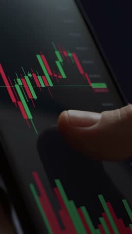 Close up of trader hand holding smartphone, using trading app with stock market charts for financial analysis and monitoring investment data. Vertical video