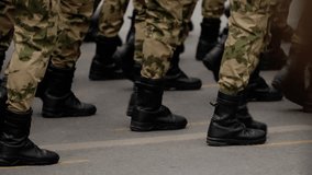 Close-up view of uniformed soldiers' legs in camouflage trousers and combat boots marching in formation along a city street, capturing synchronized steps and coordinated movement - Powered by Shutterstock - Get 15% off with code: PIKWIZARD15