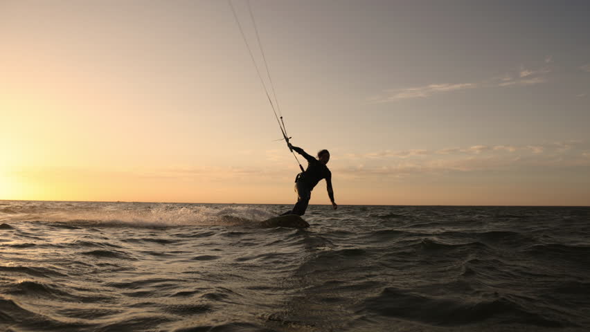 Kitesurfer enjoying ride at tropical coast sunset golden hour water spray flying symbol of freedom happiness lifestyle adventure travel destination exotic holiday paradise commercial summer vibes