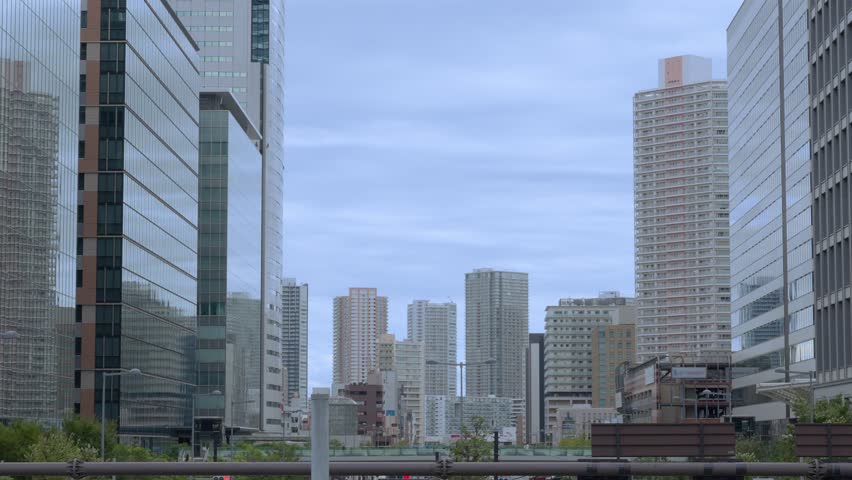 A wide shot of Tokyo's modern high-rise buildings in the Toyosu area against an overcast sky.