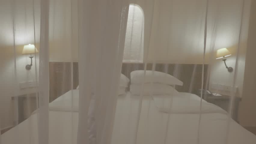 Camera moving towards hotel bed in suite with mosquito net or canopy over it. Luxury resort in African country. Five 5 star hotel room with protection against bugs and insect bites at night