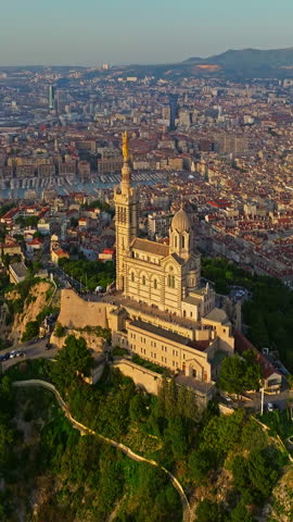  Aerial view of the Notre Dame de la Garde or Our Lady of the Guard church at sunset, southern France. The warm summer evening light illuminates the Marseille cityscape