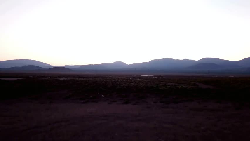 Silhouetted mountains under a vast, pale sky at dusk