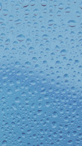 Rain-splattered windowpane with water droplets gently sliding in dim evening light, moody soft focus, ambient atmosphere, soothing scene, perfect for cinematic, introspective, melancholic visuals.