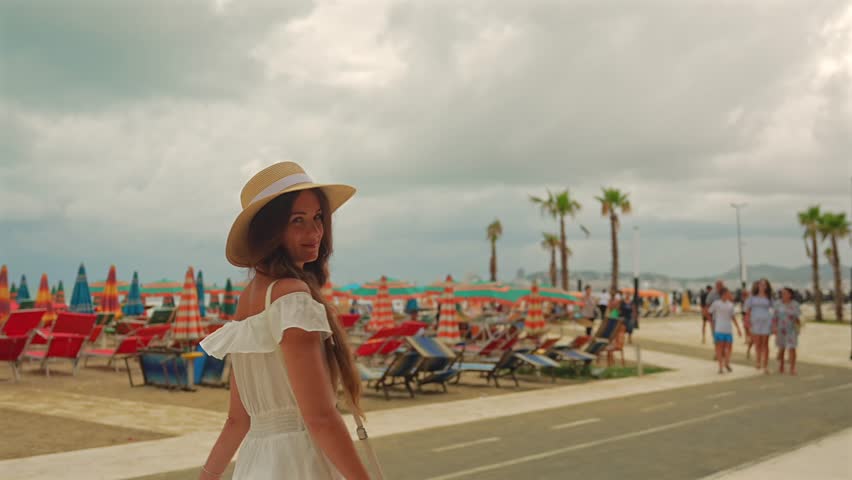 Woman walking promenade with hat and dress in Durres Albania