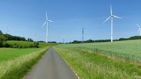 Wind turbines generating renewable electricity beside power lines below big blue summer skies.	 - Powered by Shutterstock - Get 15% off with code: PIKWIZARD15