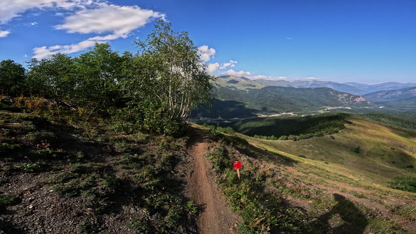 Scenic mountain trail progression through lush greenery and expansive blue skies