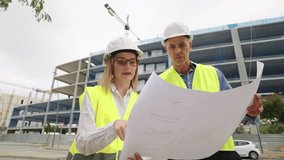 Two architects studying blueprints on a construction site - Powered by Shutterstock - Get 15% off with code: PIKWIZARD15