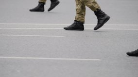 Close-up view of uniformed soldiers' legs marching in synchronized formation on a roadway, black combat boots stepping over painted lines during a parade or military drill. - Powered by Shutterstock - Get 15% off with code: PIKWIZARD15