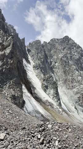 a harsh mountain landscape with a steep cliff and a glacier