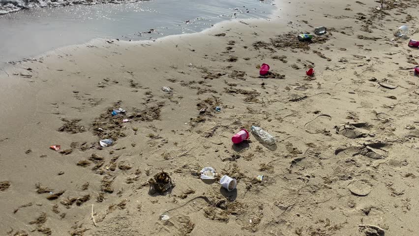 Plastic waste and trash scattered across a beach shoreline, symbolizing pollution, environmental damage, and the urgent need for ocean protection and coastal cleanup efforts.