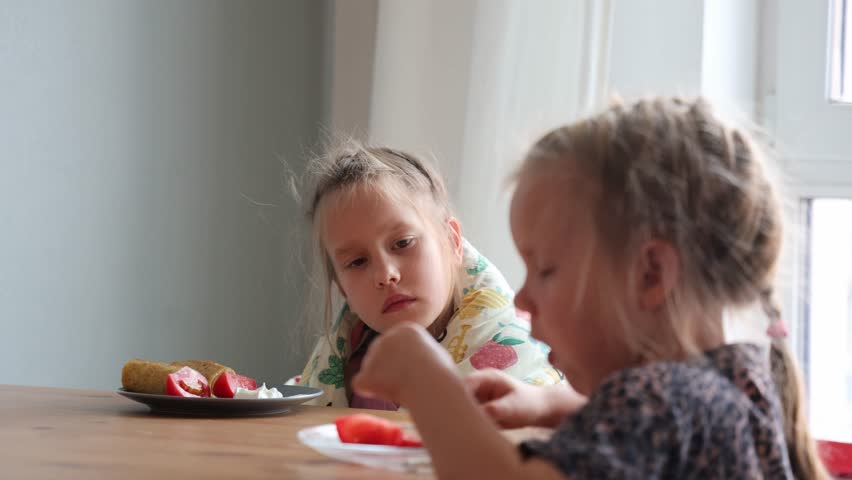 Two little sisters have pancakes for breakfast