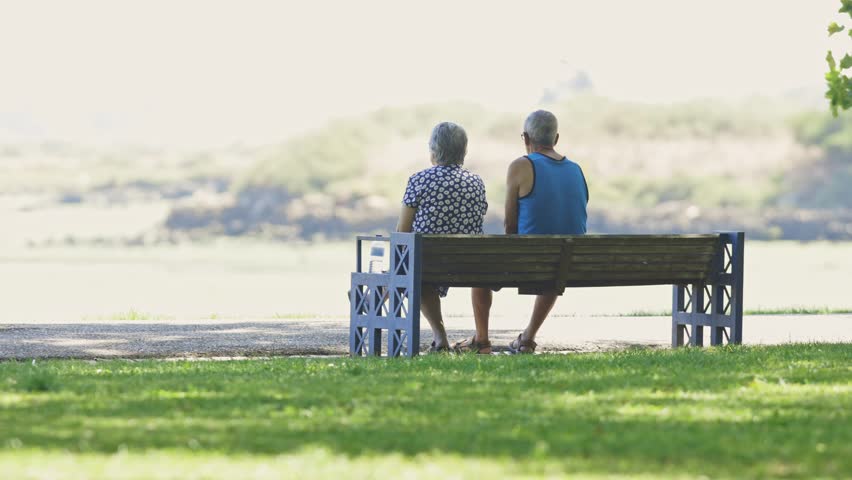 Elderly couple sitting together on a park bench
