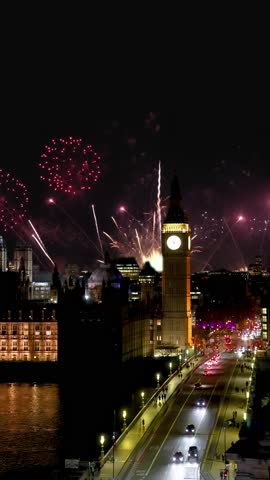 Elevated view of the Big Ben clocktower and Westminster Bridge in London, England, during night time with fireworks for new years