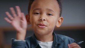 Close up serious African American boy waving hello hi greeting at home schoolboy child kid son pupil with pen looking at camera video call conference e-learning writing homework education studying - Powered by Shutterstock - Get 15% off with code: PIKWIZARD15