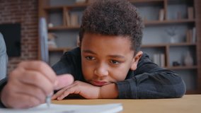 Little African American boy writing homework feeling lazy unmotivated tired son child kid write in copybook lying on table studying learning boring class lesson remote education preparing school test - Powered by Shutterstock - Get 15% off with code: PIKWIZARD15