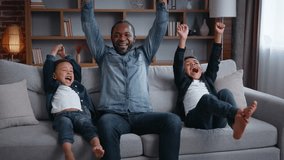 African American happy family watching TV rejoice winning sport game yelling celebrating father with two sons boys kids children watch football championship television match at home having fun laugh - Powered by Shutterstock - Get 15% off with code: PIKWIZARD15