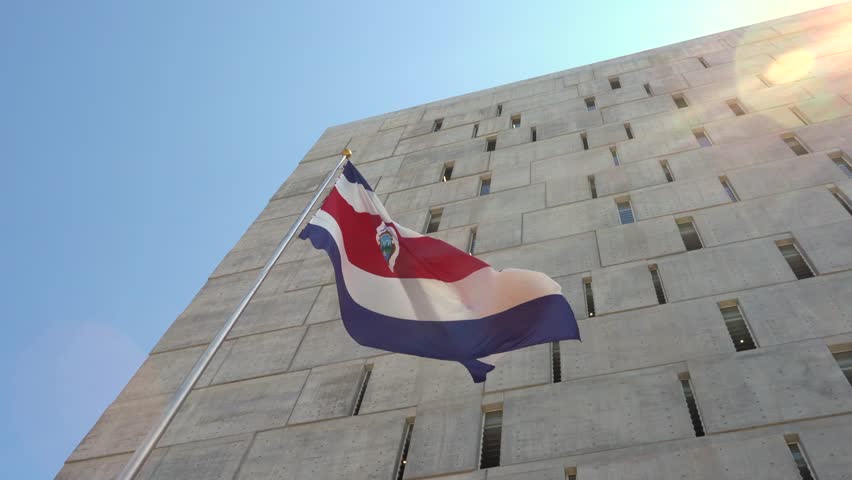 Cinematic view of the Costa Rican flag waving proudly with the Legislative Assembly building in the background, San José, Costa Rica