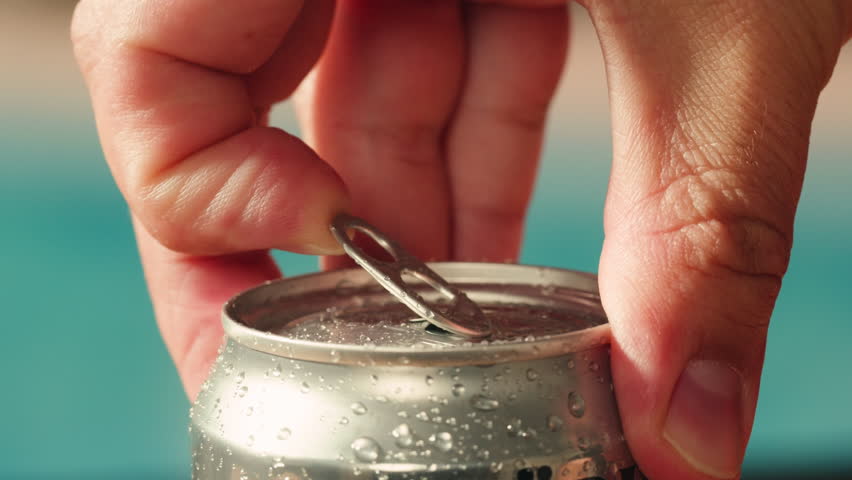 Opening soda or beer can, macro close up of can pull tab opening, watering refreshment, hand open lemonade or juice.