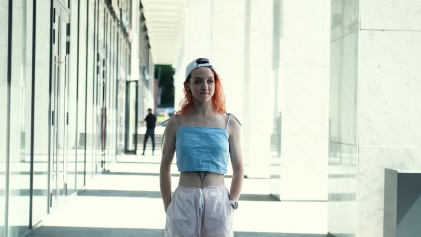 Portrait of a teenage girl with red hair standing near columns at the entrance to a business center
