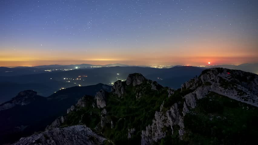 Timelapse of summer mountain landscape at moonrise with starry night sky illuminated by full moon