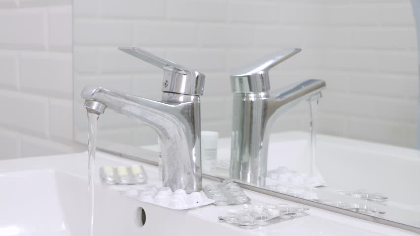 Sick Businessman Turning Off the Water from Faucet in Bathroom with Many Pills on the Sink, Facing Mirror in Silence