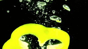 Multicolored Peppers. Slices of red, yellow and green peppers randomly fall in the water on a black background. Slow Motion - Powered by Shutterstock - Get 15% off with code: PIKWIZARD15