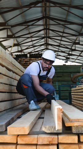 Carpenter inspecting wooden planks in lumber warehouse