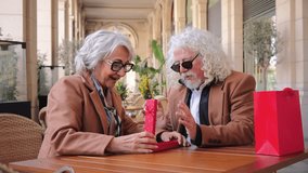 Happy senior couple eagerly unwrapping a bright red gift box, filled with joy and anticipation. Their expressions reveal the joy of sharing a special moment, strengthening their bond and affection for - Powered by Shutterstock - Get 15% off with code: PIKWIZARD15