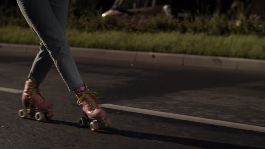 Woman legs in jeans and quad rollers glide on asphalt street