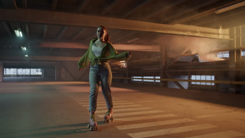 Young woman dances on roller skates in empty parking garage