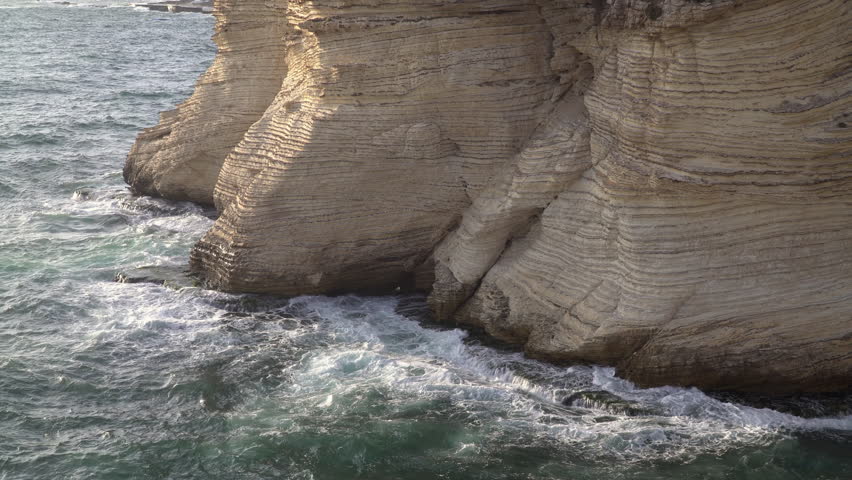 Waves crash on Pigeon Rocks, a large natural stone formation located next to the coast of Beirut, Lebanon