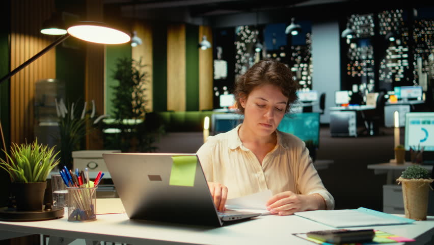 Livid businesswoman breaking a paper page after making a mistake, handwriting and notetaking in office after hours. Displeased impatient worker redoing the draft on a new sheet. Camera A.