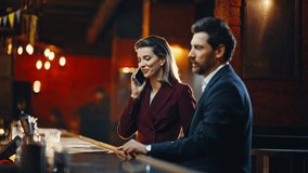 Professional team sitting close at modern lounge table indoors. Woman closing project conversation over mobile phone. Smiling colleagues making cheerful gesture waiter delivering evening cocktails - Powered by Shutterstock - Get 15% off with code: PIKWIZARD15