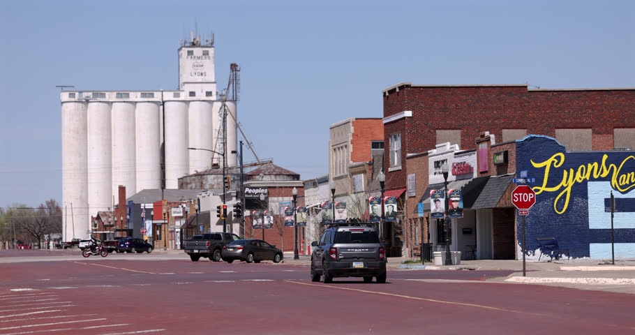 Lyons, Kansas, USA - April 6, 2025: Historic buildings stand in downtown while afternoon traffic passes.