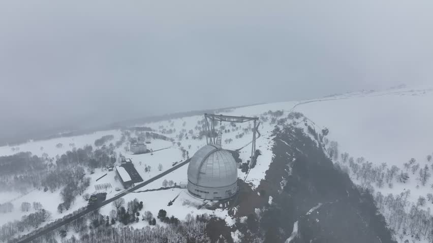 An aerial view of the BTA 6 and Special Astrophysical Observatory located in the Republic of Karachay-Cherkessia, Russia. The observatory is covered in snow on a cloudy winter day