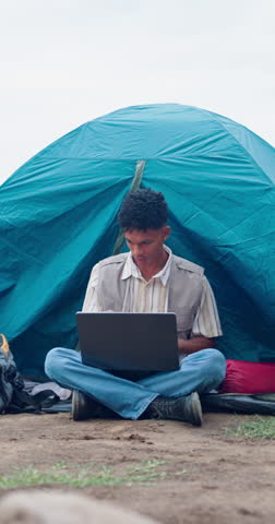 Camping, laptop and reading with man outdoor in nature to research ecosystem development. Computer, tent and typing with African person at campsite for environmental conservation or sustainability
