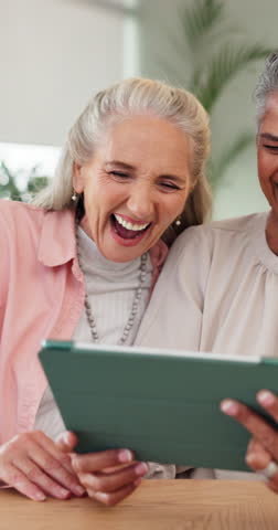 Senior friends, tablet and laughing in home for funny online video, social media meme or bonding. Retirement, happy and women with digital tech in house for comedy post, reunion visit or conversation