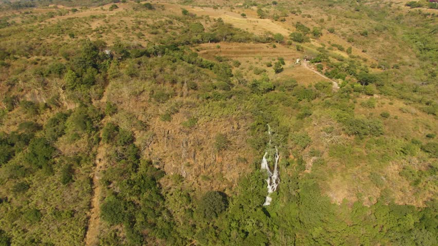 Dolly in drone shot of thin waterfall on forested hillside at Turbinas Santa Cruz, Vista Hermosa, Jalisco, Mexico